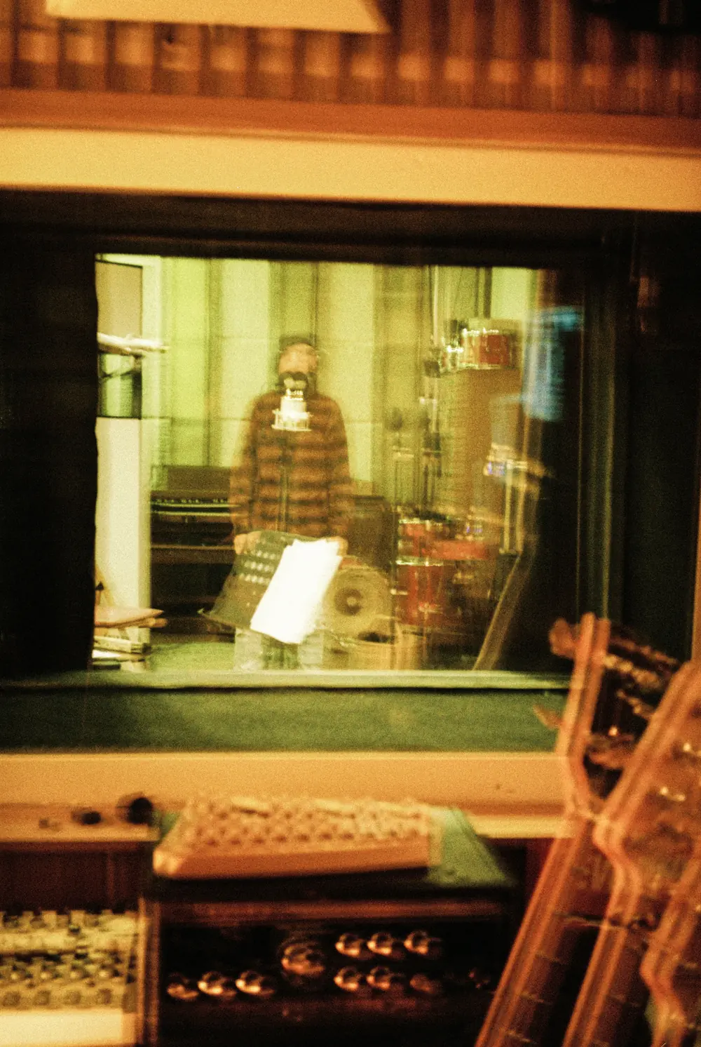 Through the studio glass, singing in the recording booth